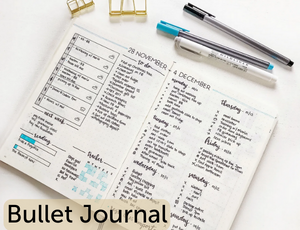 desk background with bullet journal open with writing inside. Two pens lay at the top of image. Text reads 